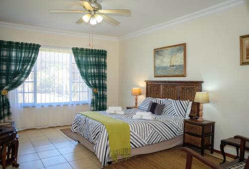 a bedroom with a bed and a ceiling fan at Crowned Crane in Gonubie