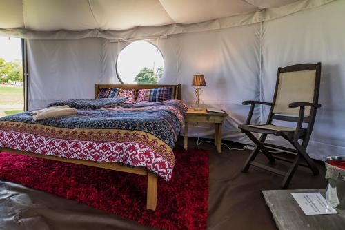a bedroom with a bed and a chair in a tent at Mousley House Farm Campsite and Glamping in Warwick