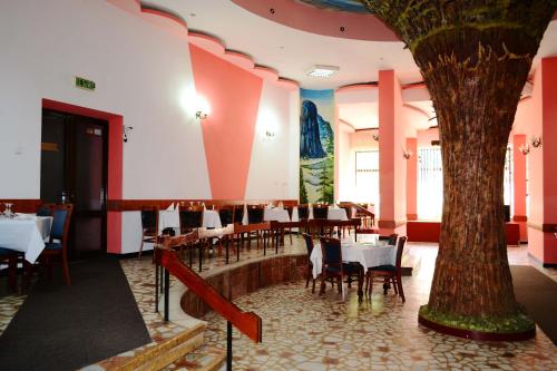 a restaurant with tables and a tree in the middle at Hotel Bradul in Durau
