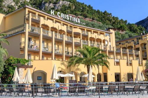 a hotel with tables and umbrellas in front of it at Hotel Cristina in Limone sul Garda