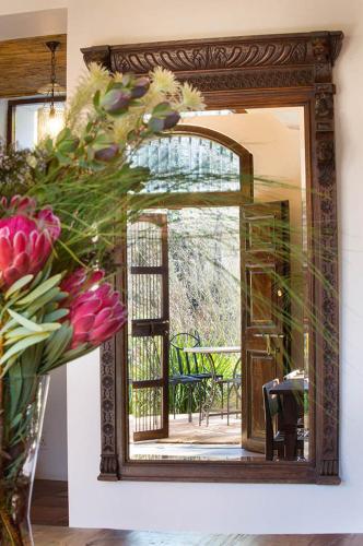 a mirror with a vase of flowers in a room at Bartinney Private Cellar Banhoek in Stellenbosch