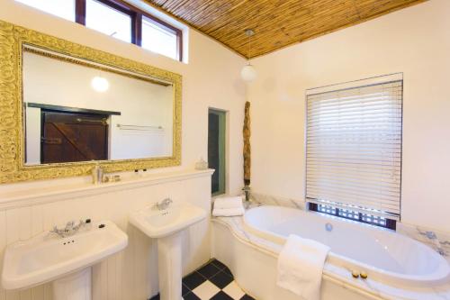 a bathroom with a tub and a sink and a mirror at Bartinney Private Cellar Banhoek in Stellenbosch