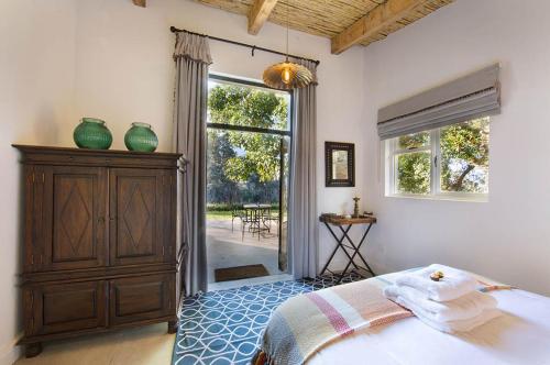 a bedroom with a bed and a dresser and a window at Bartinney Private Cellar Banhoek in Stellenbosch
