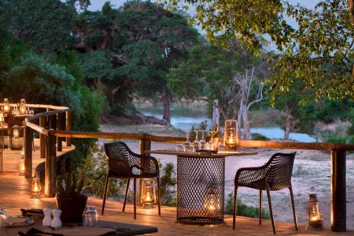 a table and chairs on a deck with lights at Lion Sands Ivory Lodge in Sabi Sand Game Reserve