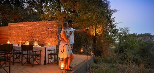 a man and a woman standing next to a table at Lion Sands Ivory Lodge in Sabi Sand Game Reserve