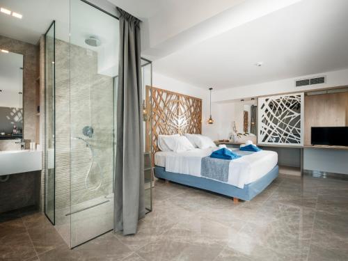 a bedroom with a bed and a glass shower at Lymberia Hotel in Faliraki