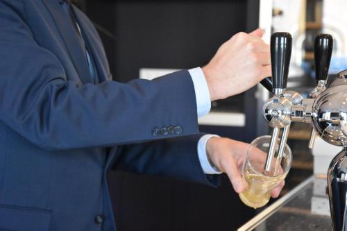 Ein Mann im Anzug, der einen Drink in ein Glas gießt. in der Unterkunft Blue Mansion Hotel in Aalsmeer