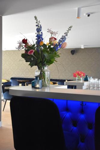a vase of flowers sitting on a table with chairs at Blue Mansion Hotel in Aalsmeer