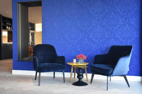 two chairs and a table in front of a blue wall at Blue Mansion Hotel in Aalsmeer