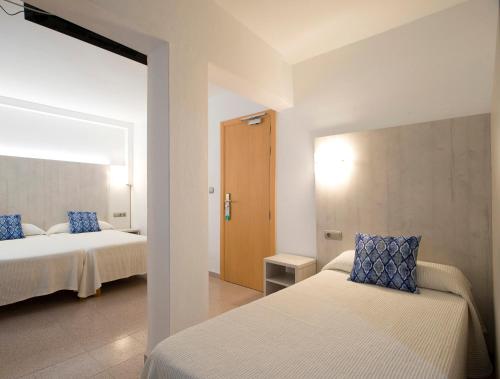 a bedroom with two beds with blue pillows at Hostal Roca in San Antonio