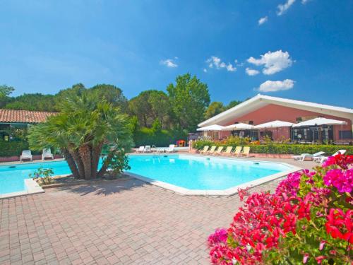 una piscina en un complejo con flores rosas en Apartment Relais-1 by Interhome, en Marina di Bibbona