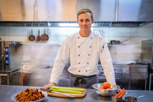a chef standing in a kitchen with a plate of vegetables at Lion Sands Ivory Lodge in Sabi Sand Game Reserve