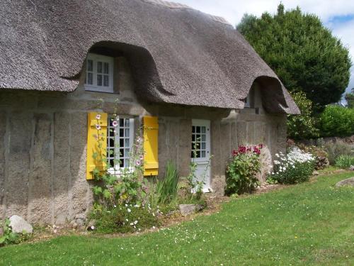 a small stone cottage with a thatched roof at Holiday Home Chaumiere Natelliou by Interhome in Trégunc