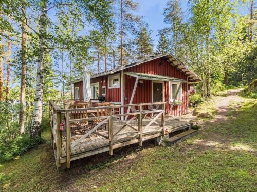 une cabine rouge avec une terrasse couverte dans les bois dans l'établissement Holiday Home Artturin mökki by Interhome, à Kylmälä