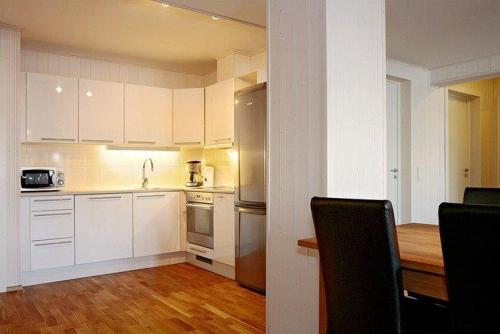 a kitchen with white cabinets and a wooden floor at Skarsnuten Apartments in Hemsedal
