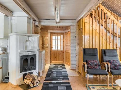 a log cabin with a fireplace and two chairs at Holiday Home Riekonmarja by Interhome in Äkäslompolo