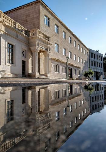 an old building with its reflection in the water at Vila Maslinica in Pučišća