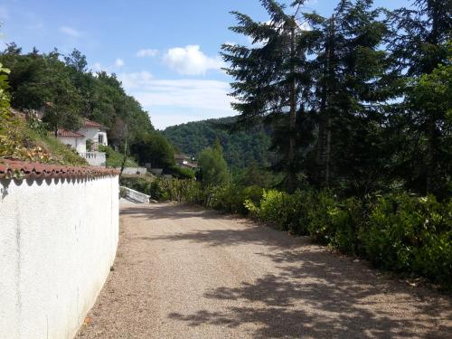 a dirt road next to a white wall and trees at Ma villa au bord de l'eau in Miremont