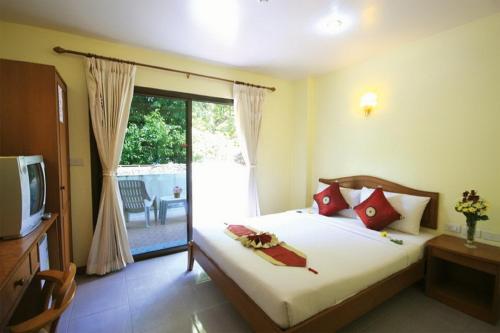 Un dormitorio con una cama y un televisor y un balcón. en Amorn Mansion, en Ao Nang Beach