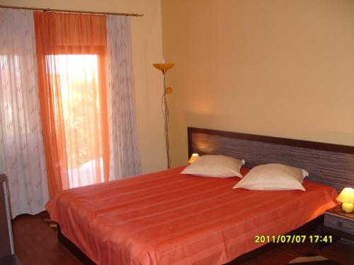 a bedroom with a bed with a orange blanket and a window at Pensiunea Ruxandra in Baile Unu Mai