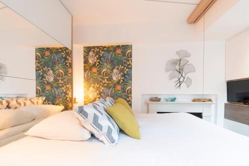 um quarto com uma cama branca e papel de parede floral em Le Petit Botte em Rennes