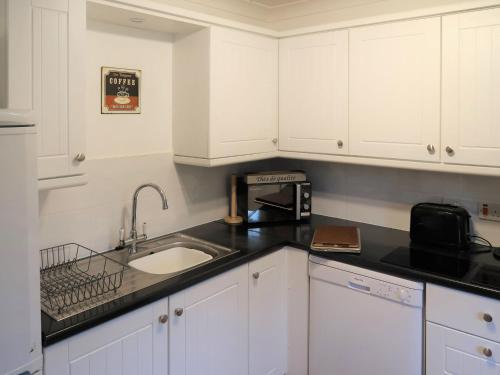 Holiday Home Woodhouse-4 by Interhome في Shermanbury: مطبخ مع دواليب بيضاء ومغسلة