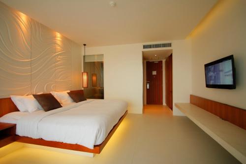 a bedroom with a white bed and a flat screen tv at G Hua Hin Resort & Mall in Hua Hin