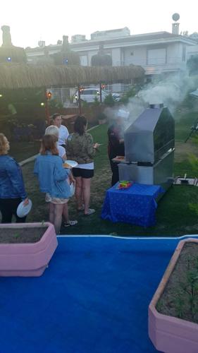 a group of people standing around a blue table with a grill at Grand Yayla Hotel in Cesme