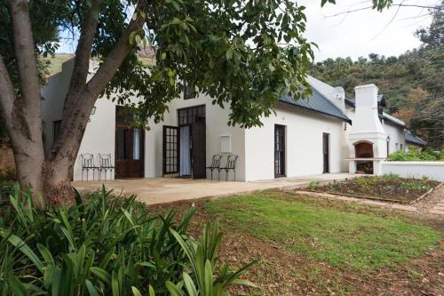 a white house with a tree in front of it at Bartinney Private Cellar Banhoek in Stellenbosch