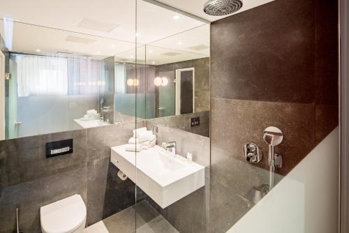 ein Badezimmer mit einem Waschbecken, einem WC und einem Spiegel in der Unterkunft Cityhotel am Thielenplatz in Hannover