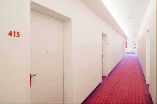 a corridor with white doors and a red carpet at Cityhotel am Thielenplatz in Hannover