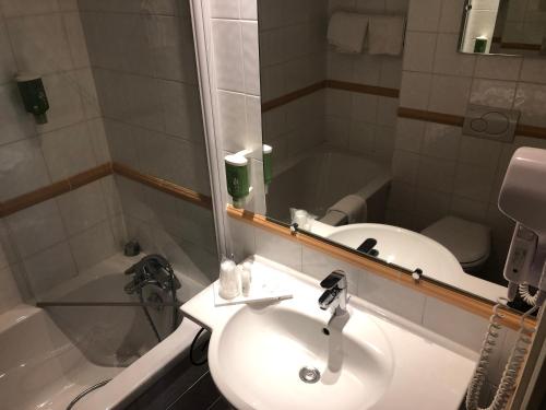 La salle de bains est pourvue d'un lavabo, d'un miroir et d'une baignoire. dans l'établissement Castex Hotel, à Paris