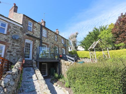 an old stone house with a garden in front of it at Bryn Teg Cottage in Menai Bridge