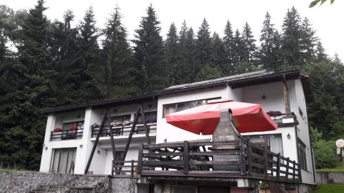 a red umbrella sitting in front of a house at Timis Valley, Casa Eni&Dan in Predeal