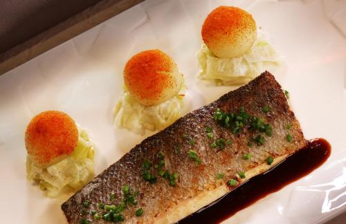 a white plate with a piece of fish and potatoes at Le Tillau in Les Verrières-de-Joux