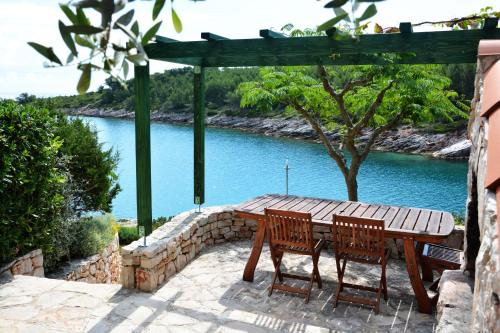 a wooden table and chairs with a view of a river at Bay House Rosohotnica in Vrboska