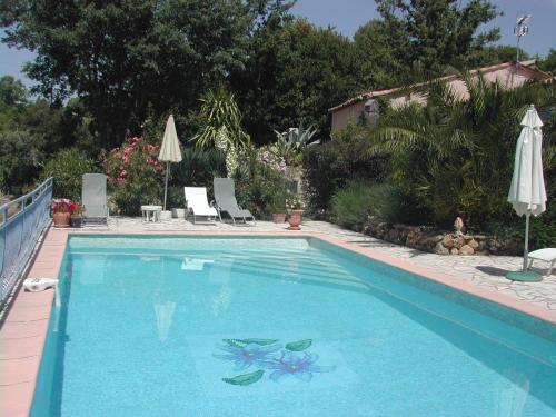 una piscina blu con due sedie e un ombrellone di la bergerie a Tourtour