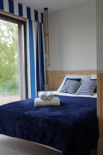a bedroom with a blue bed with towels on it at Przy morzu in Dziwnówek