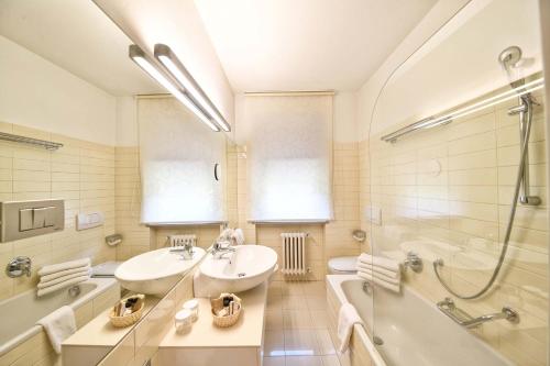 a bathroom with a sink and a tub and a shower at Hotel Juliane in Merano
