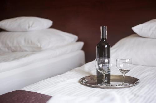 a bottle of wine and two glasses on a bed at Vinci Hotel Airport in Modlniczka