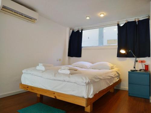 a bedroom with a bed with white sheets and a window at AirTLV - Centrally Located Studio With Gallery in Tel Aviv