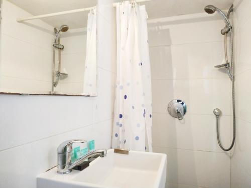 a white bathroom with a sink and a shower at AirTLV - Centrally Located Studio With Gallery in Tel Aviv