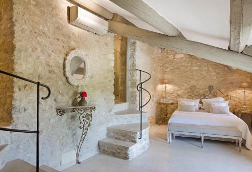 a bedroom with a bed and a stone wall at Villa Grenache, La Bastide de Marie, Villa avec services in Ménerbes