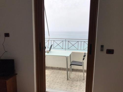 a room with a table and a chair and the ocean at Qeparo Antonio Rooms in Qeparo
