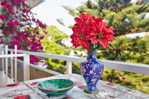 a blue vase with red flowers sitting on a table at Pettas Apartments in Zakynthos Town
