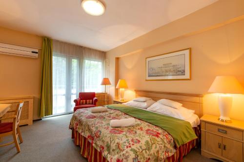 sypialnia z dużym łóżkiem i czerwonym krzesłem w obiekcie Hotel Fit Hévíz w Hévízie
