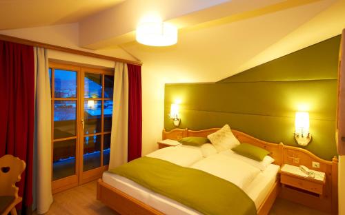 a bedroom with a green and white bed and a window at Hotel Lisa in Flachau
