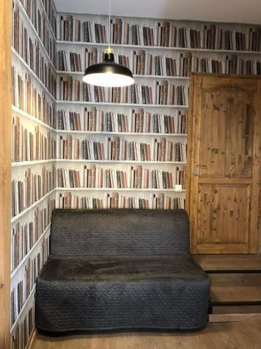 a room with a wall filled with books and a bench at Tulipán Villa Panzió in Szolnok