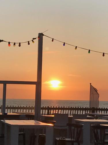 a sunset over the beach with tables and a pier at Appartement 't Loft in Zandvoort