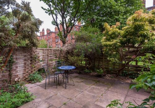 a patio with a table and chairs in a garden at The Lauderdale Street Residence in Edinburgh